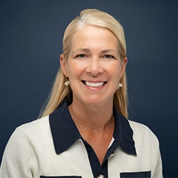 Tami Culver smiles into the camera against a dark blue background.